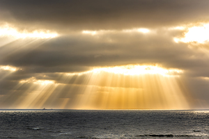 Dramatic clouds and God rays over the North Sea at the coast of the island of Sylt in Germany
