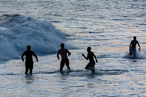 Boys playing in the waves at Ipanema Beach in Rio de Janeiro in Brazil at sunset  