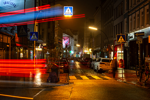 Long exposure night shot of a colourfully lit up street and zebra crossing in Hamburg Altona