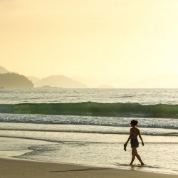 Woman walking along Copacabana Beach in Rio de Janeiro in Brazil at sunrise 