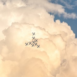 Fighter jets flying in a triangle formation during airshow in scenic clouds