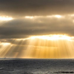 Dramatic clouds and God rays over the North Sea at the coast of the island of Sylt in Germany