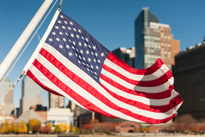 US flag floating with New York city buildings