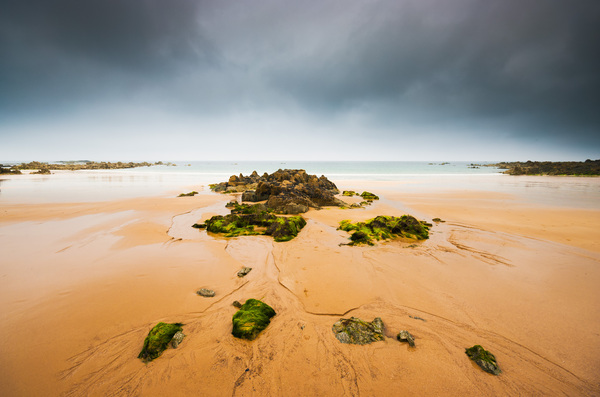 Empty beach with rocks and dark sky  Print