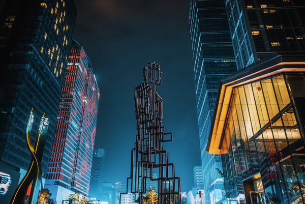 Illuminated skyscrapers and metallic statue at night in Chengdu by Philippe Lejeanvre