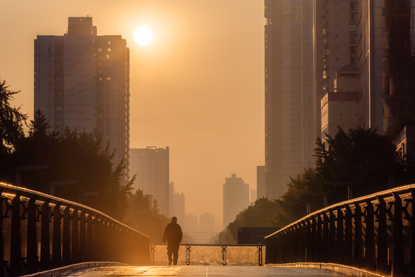Man walking on a foot bridge against sunrise by Philippe Lejeanvre