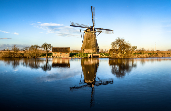 Windmill reflecting in water at sunset Print