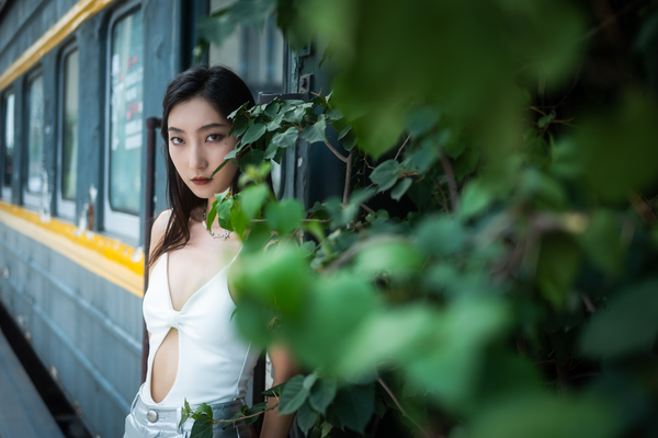 Young woman standing against a old train portrait by Philippe Lejeanvre