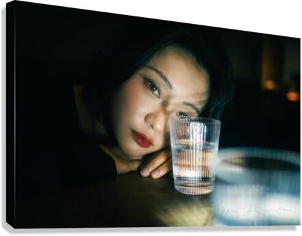 Young woman looking through a glass of water Canvas Print