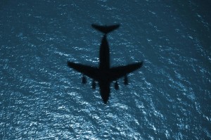 Silhouette of a military aircraft in flight over the Atlantic Ocean.