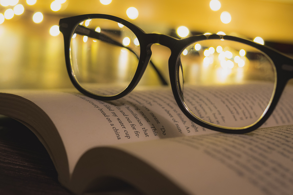 A pair of reading glasses on a open book by Jurica Tomic Svarun