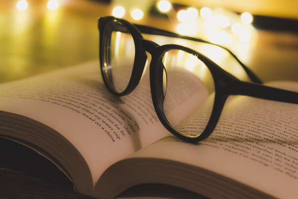 A pair of reading glasses on a open book by Jurica Tomic Svarun