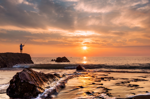 Widemouth bay sunset with lone fisherman