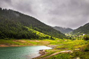 Serene Mountain Lake with Lush Greenery and Misty Clouds