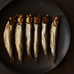 Small smoked fish on black plate
