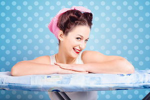 Happy 60s pinup housewife on blue ironing board