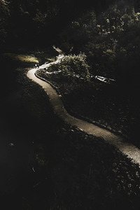 Distant people walking on winding dark path