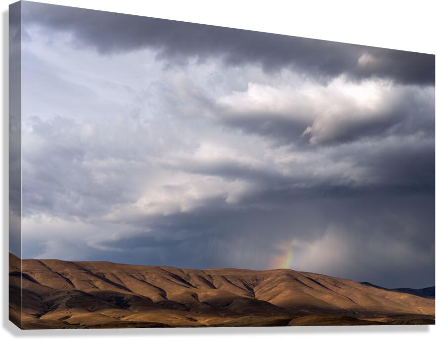 Rainbow with diagonal clouds over morning light on mountains Canvas Print