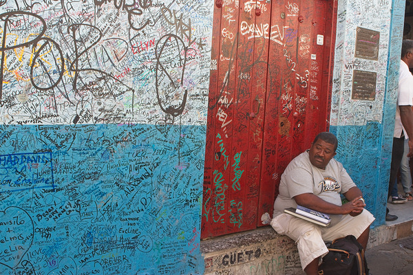 Graffiti-Covered Wall with Seated Man by Chirag Pandya