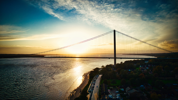 Sunset view of a suspension bridge over a river with vibrant skies and reflective water in Hull England. by Vasile Jechiu