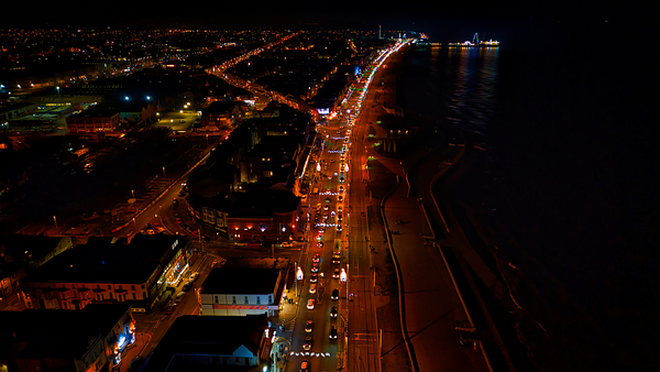 Aerial night view of a coastal city with illuminated streets and dark ocean waters in Backpool England. by Vasile Jechiu