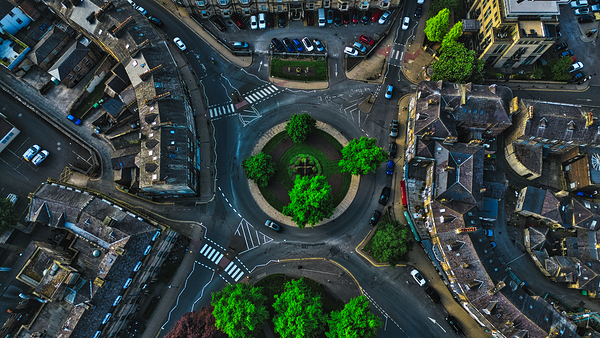 Aerial view of a roundabout with green trees and surrounding buildings in Harrogate North Yorkshire by Vasile Jechiu
