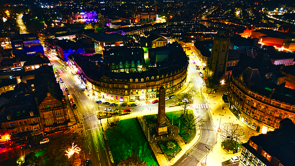 Aerial night view of a vibrant cityscape with illuminated streets and buildings showcasing urban architecture in Harrogate North Yorkshire. by Vasile Jechiu