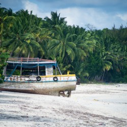 Fishing ship boat stranded on white sand beach