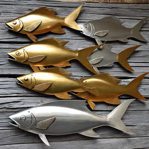 Golden and silver fish sculptures on wood wall art