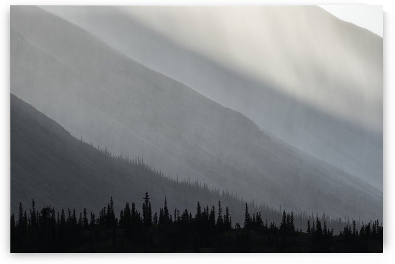 Light shines through the rain as it falls on the mountains along the Wind River in the Peel Watershed; Yukon, Canada by PacificStock