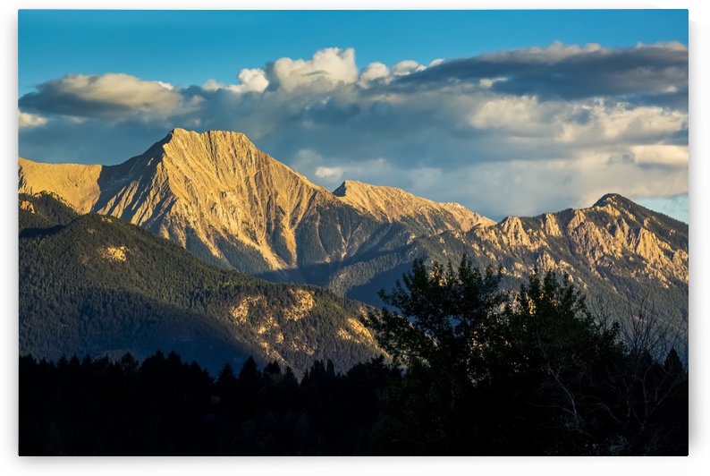 Dramatically lit mountain range at sunset with clouds and blue sky; Invermere, British Columbia, Canada by PacificStock