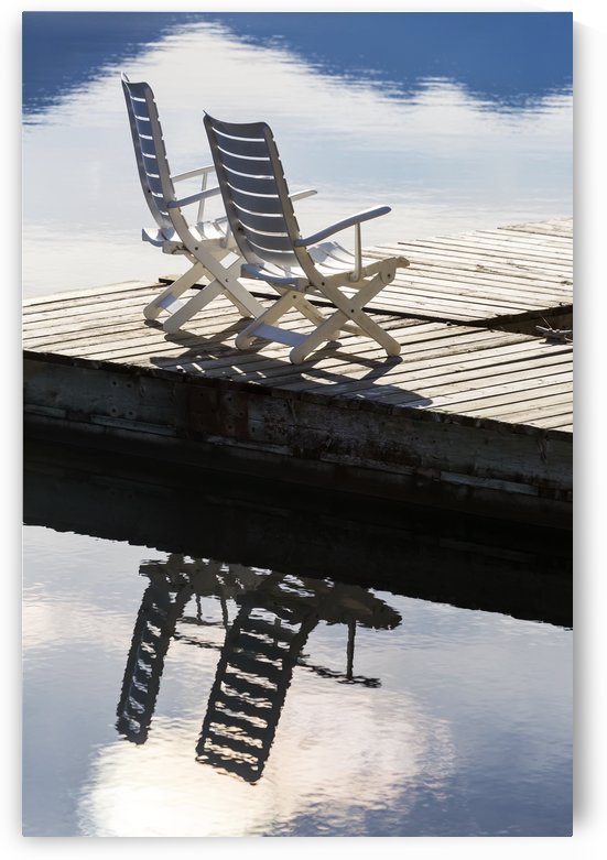 Two white wooden deck chairs on wooden boat dock reflecting in the water; Invermere, British Columbia, Canada by PacificStock