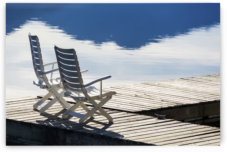 Two white wooden deck chairs on wooden boat dock reflecting in the water; Invermere, British Columbia, Canada by PacificStock