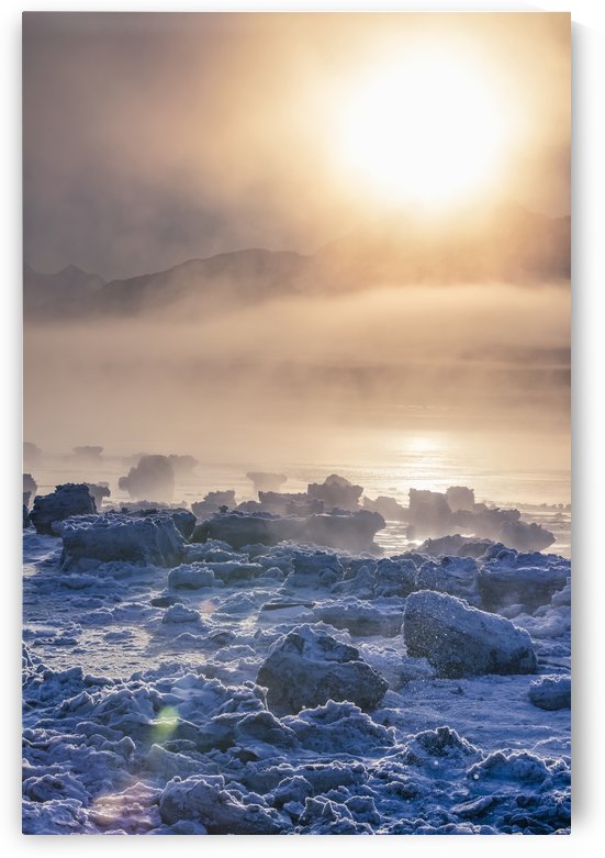 Low altitude fog is cast in warm sunset light along Turnagain Arm and the Seward Highway in winter, sea ice covering the ocean in the foreground, the Chugach Moutains revealed in the background, South-central Alaska; Alaska, United States of America by PacificStock