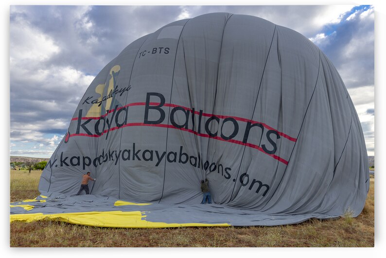 men deflate a hot air balloon at the end of a sightseeing tour by Gualtiero Boffi