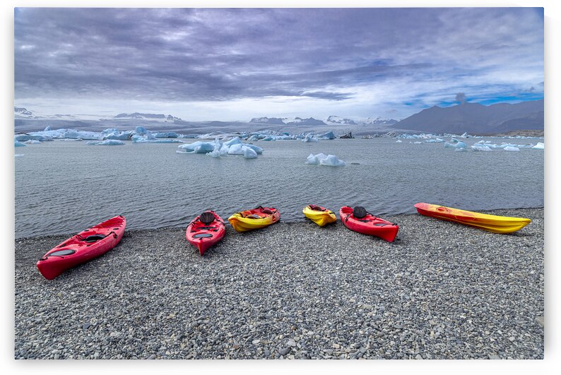 Colorful kayaks resting on a rocky beach awaiting kayakers in ic by Gualtiero Boffi
