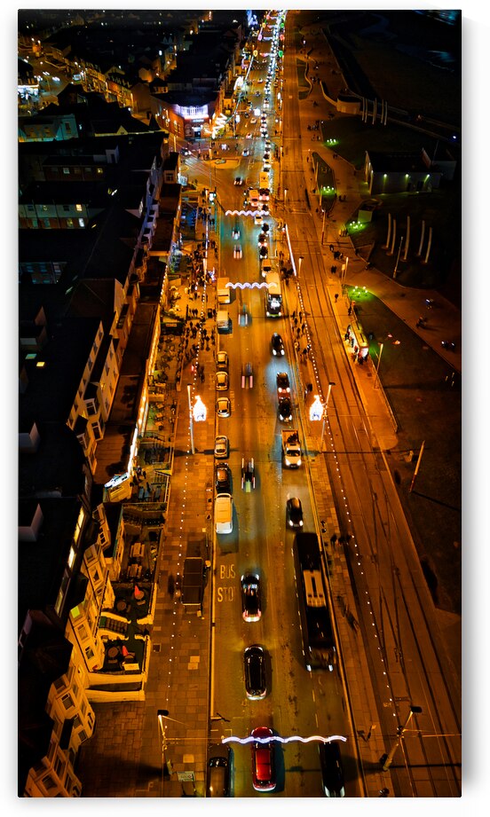 Aerial night view of a bustling city street with glowing traffic lights and cars in motion in Backpool England. by Vasile Jechiu