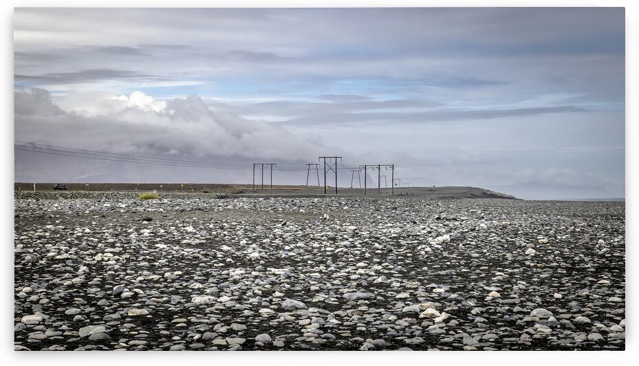 Electricity pylons crossing a desolate rocky plain in iceland by Gualtiero Boffi