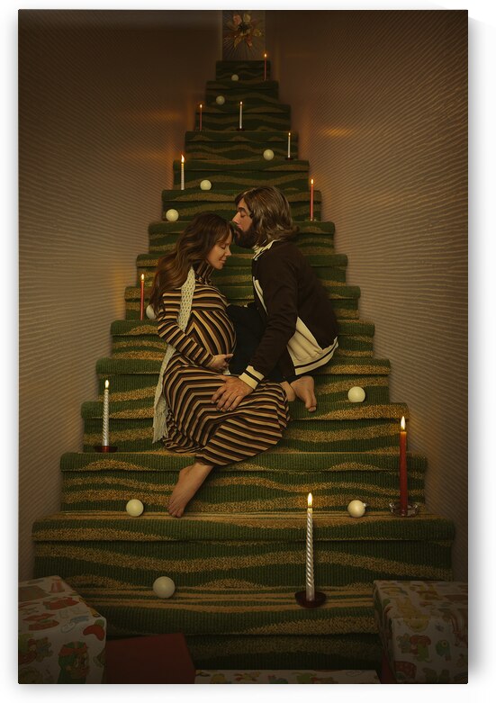 Vintage scene of a man and a pregnant woman from the 1970s sitting in a staircase creating the illusion of a Christmas tree loving each other surrounded by candles ornaments and gifts by Artmood Visualz