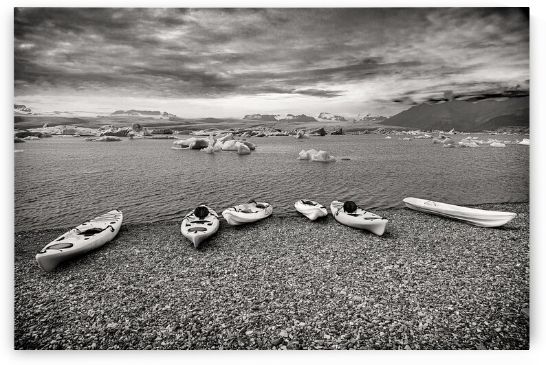 Colorful kayaks resting on a rocky beach awaiting kayakers in ic by Gualtiero Boffi