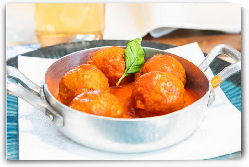 Traditional meatballs served with a basil leaf and tomato sauce. by Paolo Modena