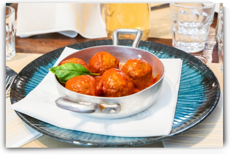 Traditional meatballs served with a basil leaf and tomato sauce. by Paolo Modena
