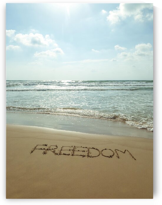 Word Freedom written in sand on the beach by Assaf Frank