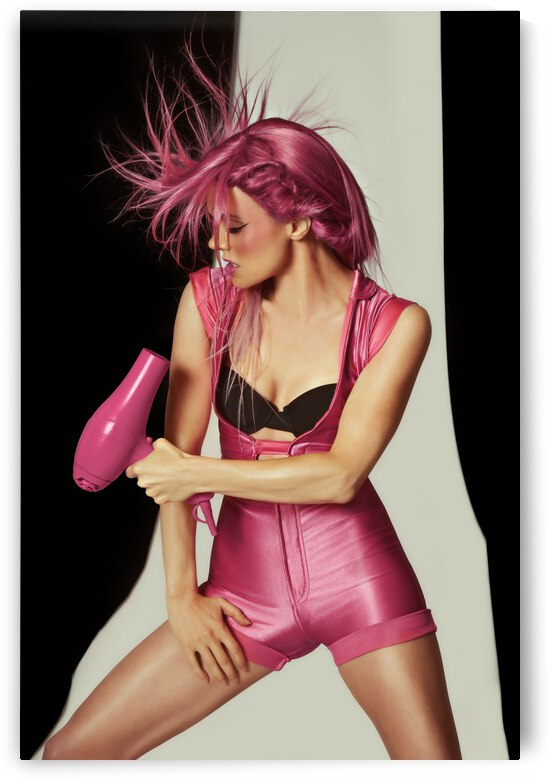 Portrait of a young woman in a pink one-piece jumpsuit  with a hair dryer her raspberry colored hair flying around by Artmood Visualz