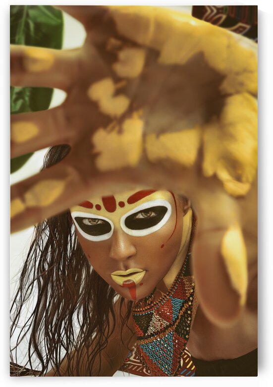 Portrait of a young woman with a tribal look makeup and wet hair wearing a traditional bead necklace her yellow painted hand in front of the camera by Artmood Visualz