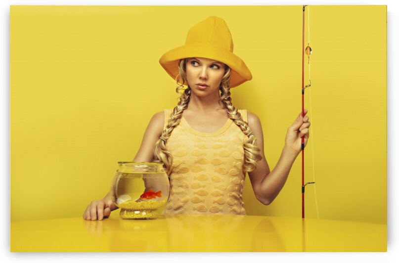 Portrait of a young fisherwoman  patiently waiting dressed in a yellow dress with a fish pattern fishing a goldfish in its fishbowl placed on a yellow table sitting in front of a yellow background by Artmood Visualz