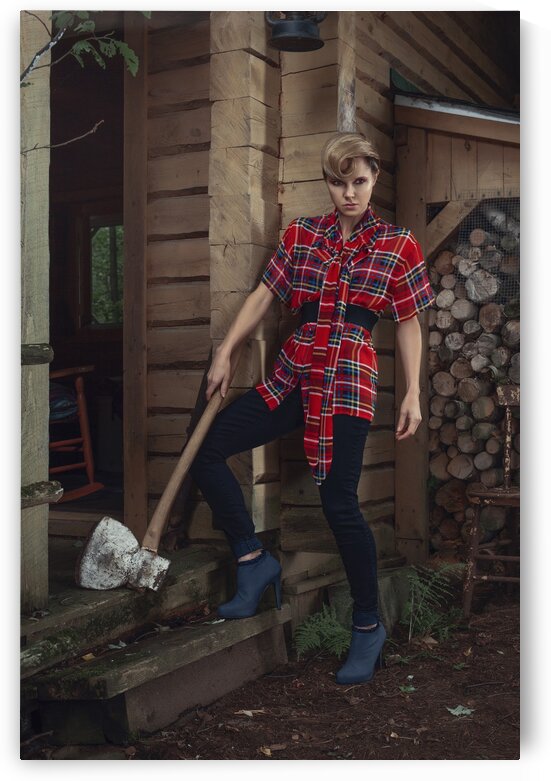 Beautiful young blonde woman with a curl in her hair wearing a long plaid shirt standing on the stairs of a rustic wooden shack an antique axe leaning against her leg by Artmood Visualz