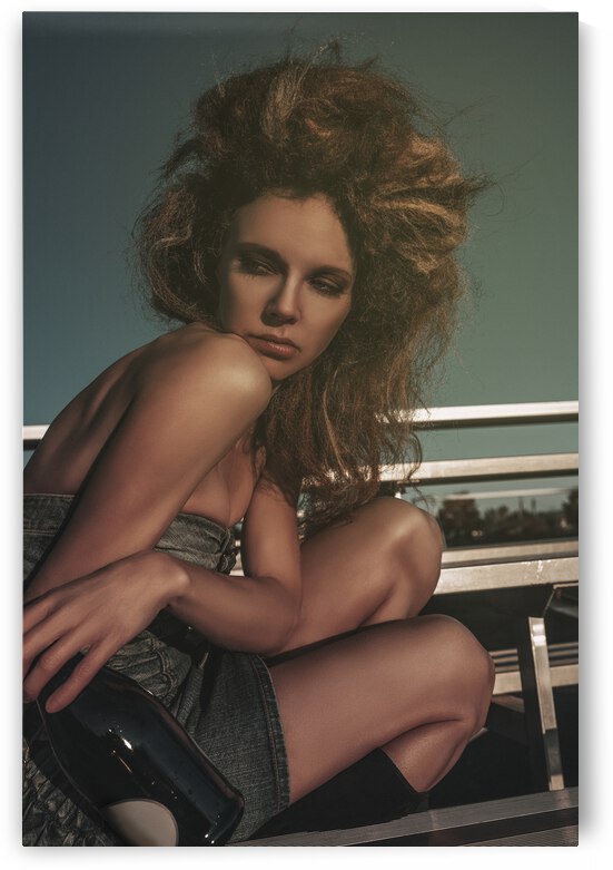 Vintage portrait of a tipsy beautiful young woman wearing an old school denim dress and long teased hair celebrating alone with champagne in the bleachers of a soccer field by Artmood Visualz