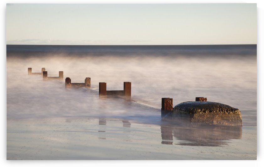 Wooden Posts And Boulders Immersed In Water At The Coast; Northumberland, England by PacificStock