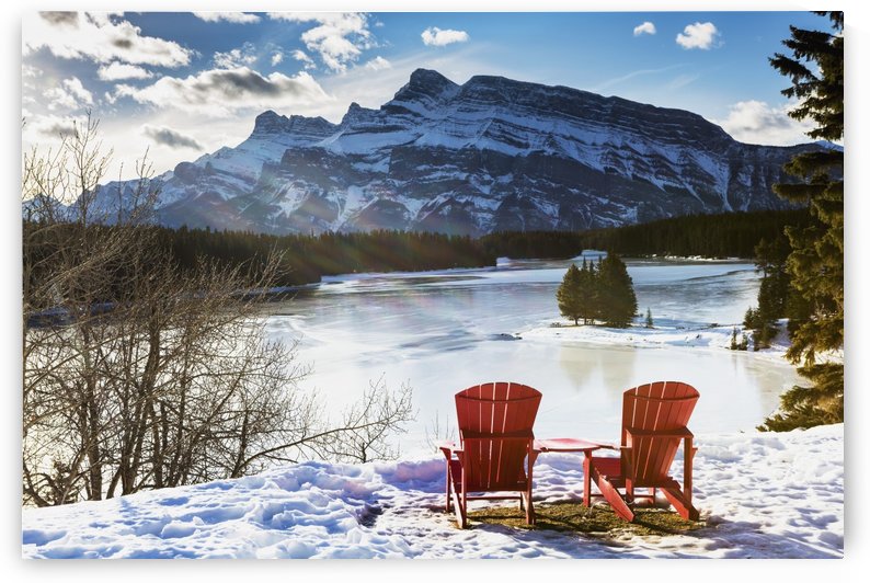 Two red chairs on snow covered ridge overlooking frozen lake with snow covered mountain in the background with blue sky and clouds; Banff, Alberta, Canada by PacificStock
